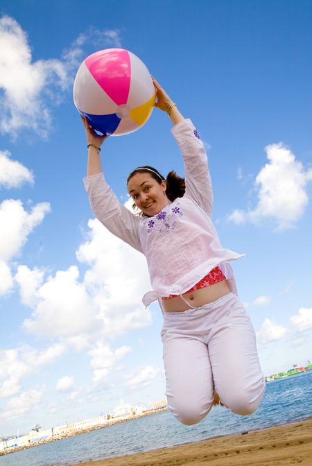 girl having fun at the beach with a beachball on a sunny day
