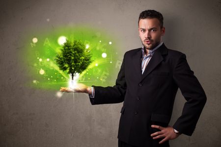Young businessman holding a glowing tree in his hand
