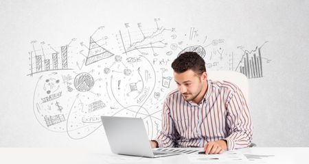 Business man at desk with hand drawn charts at the background