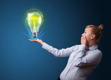 Young businesswoman holding glowing lightbulb in her hand
