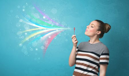 Beautiful girl blowing abstract colorful bubbles and lines on blue background