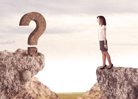 Businesswoman standing on the edge of mountain with a rock question mark on the other side