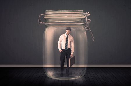 Businessman trapped into a glass jar concept on background