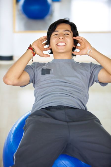 Man at the gym doing sit-ups on a pillates ball