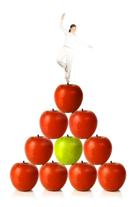 balancing diet - woman balancing on red apples on a pyramid shape over a white background