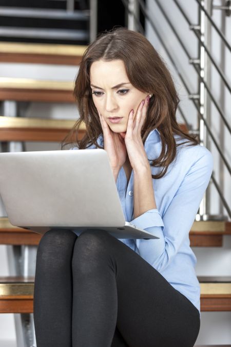 Young woman using a laptop computer looking concerned and worried