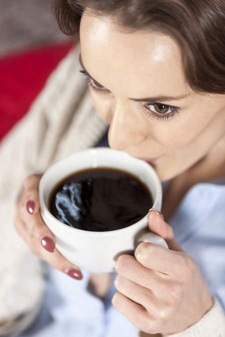 Beautiful young woman enjoying a fresh cup of coffee in a coffee shop
