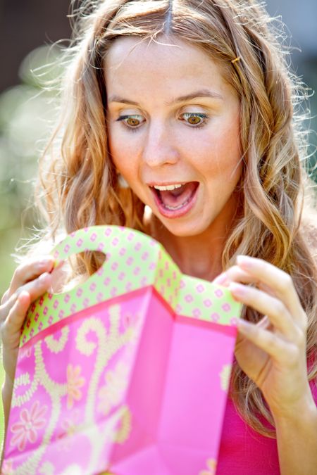 Suprised woman opening a gift outdoors