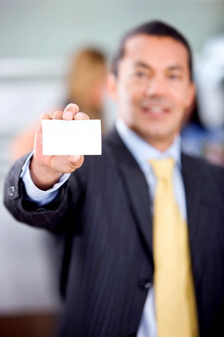 Businessman showing his business card in an office smiling
