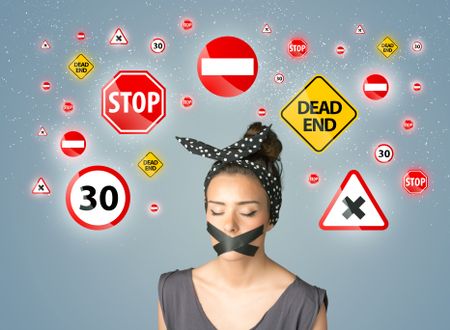 Young woman with taped mouth and traffic signals around her head