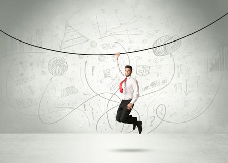 Businessman hanging on a rope with analysis and graphs background