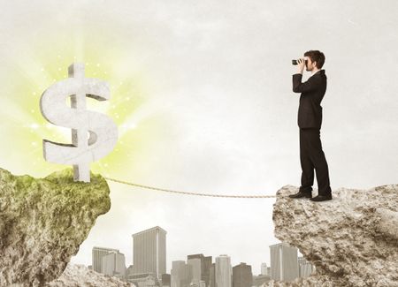 Businessman standing on the edge of mountain with a shining dollar mark on the other side 
