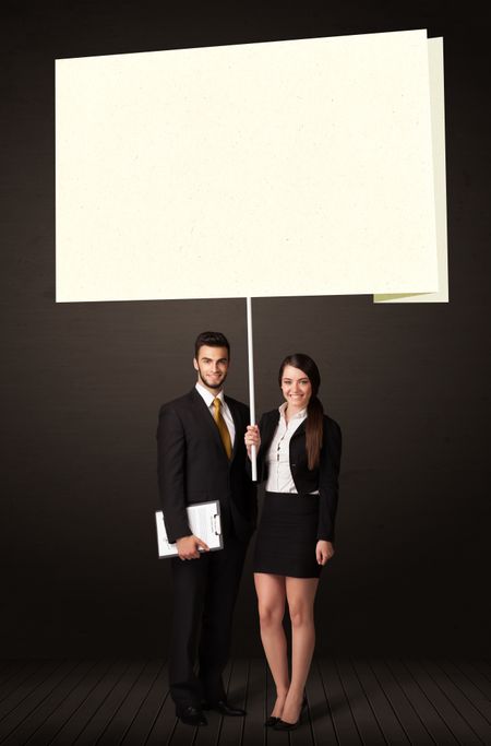 Young business couple holding a big, white post-it paper