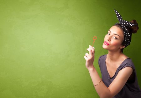 Beautiful woman blowing soap bubble on copyspace green background