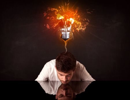 Depressed businessman sitting under a blowing idea bulb
