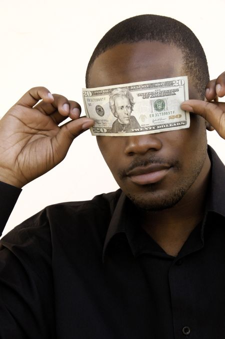 Young black man holding a U.S. $20 bill over his eyes