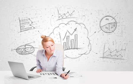 Business woman sitting at white table with hand drawn graph charts