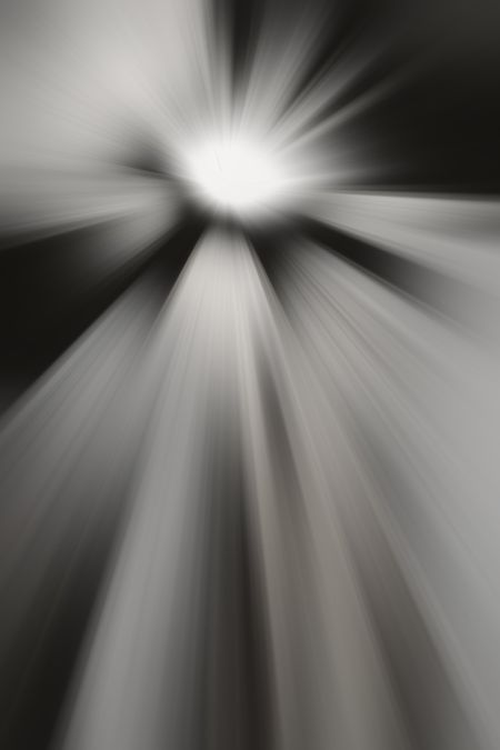 Black and white radial blur of bright object emitting rays in every direction, for themes of origin, radiance, interstellar travel