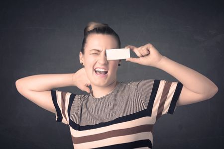 Pretty girl holding blank copy space paper at her eyes concept