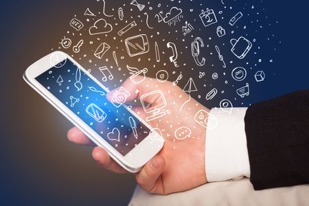 Hand holding smartphone with hand drawn media icons and symbols concept