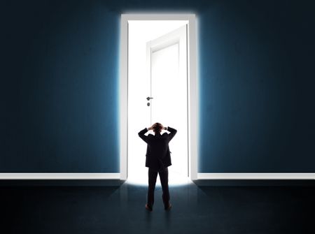 Business man looking at big bright opened door concept