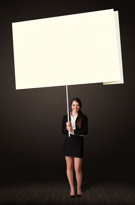 Young businesswoman holding a big, white post-it paper
