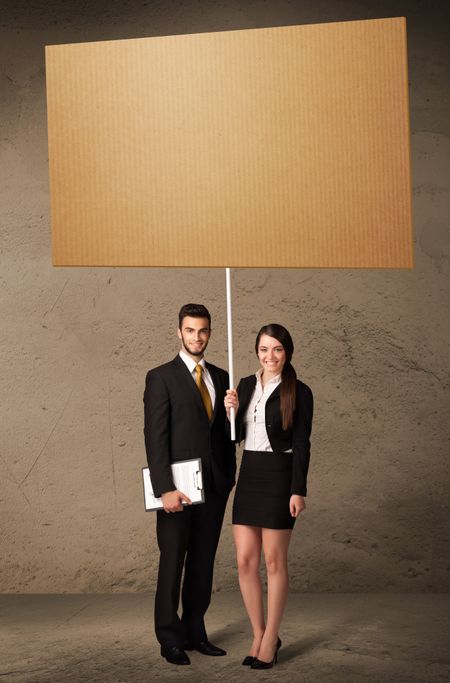 Young business couple holding a blank cardboard