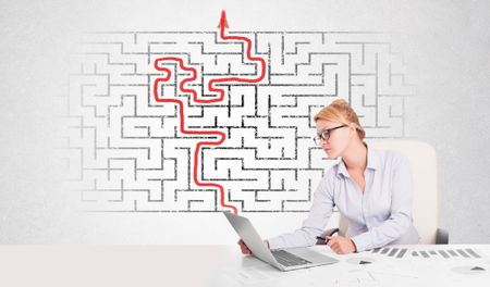 Business woman at desk with labyrinth in the background