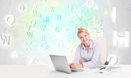 Business woman at white desk with green word cloud