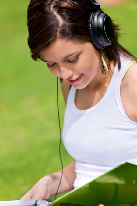 Casual woman listening to music while studying outdoors
