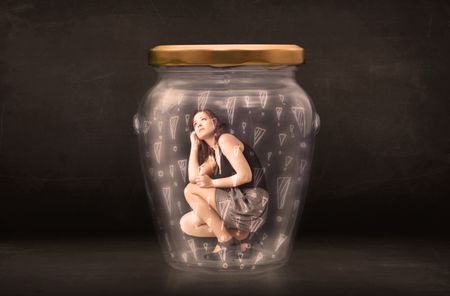 Business woman trapped in jar with exclamation marks concept on bakcground