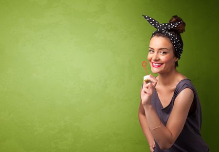 Beautiful woman blowing soap bubble on copyspace green background