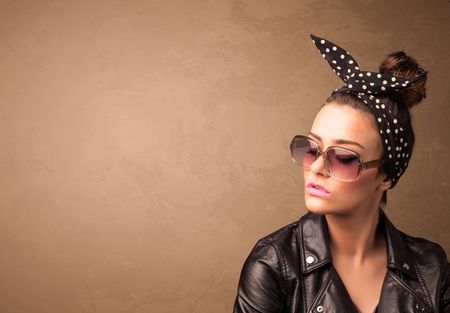 Portrait of a young pretty woman with sunglasses and copyspace on brown background