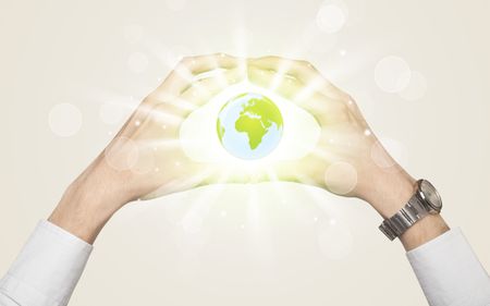 Hands creating a form with shining globe in the center
