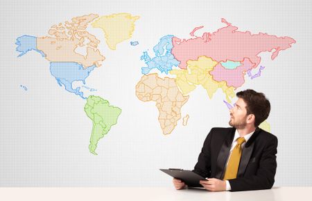 Businessman sitting at white table with colorful world map background