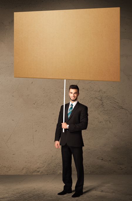 Young businessman holding a blank brown cardboard
