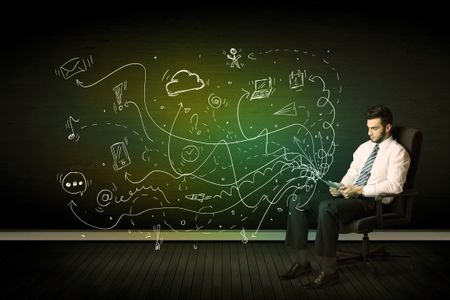 Businessman sitting in chair holding tablet with media icons concept on background