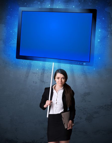 Young businesswoman holding a big, blue shining tablet
