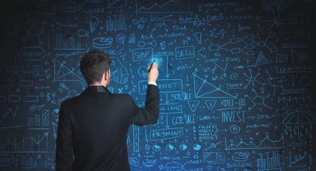 Businessman drawing business schemes on glass wall