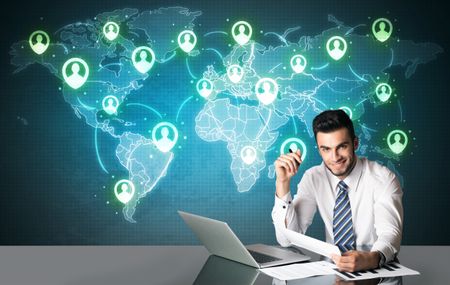 Businessman sitting at table with social media connection symbols on the world map

