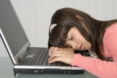 Girl in pink asleep, head and hands resting on computer keyboard