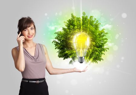 Young girl presenting idea light bulb with green tree concept