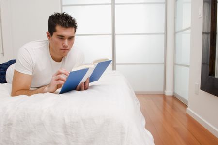 A guy reading on a bed.