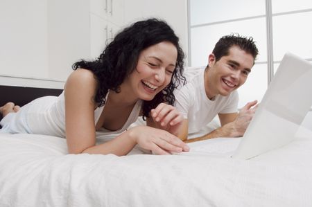 A couple laughing while looking at the computer.