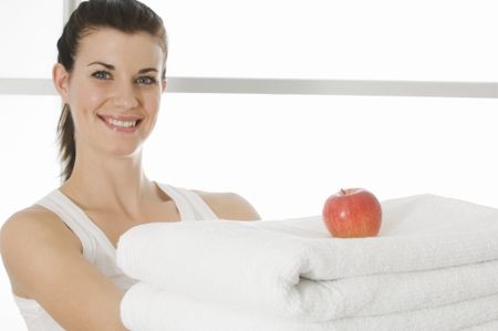 Girl holding towels with apple on top.