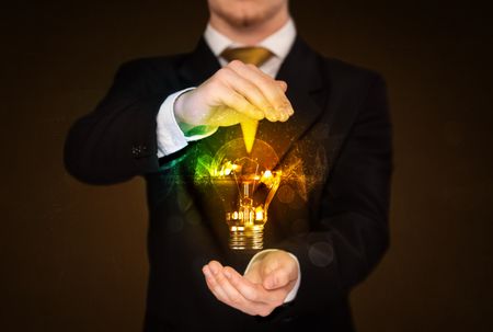 Businessman holding a shining light bulb in front of his body