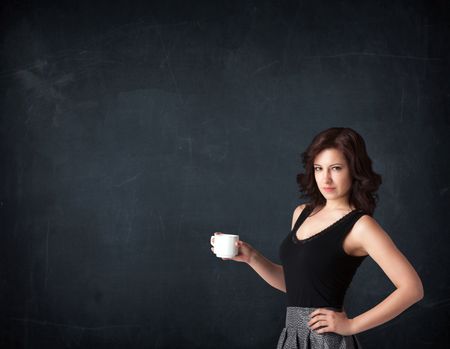 Businesswoman standing and holding a white cup on a black background
