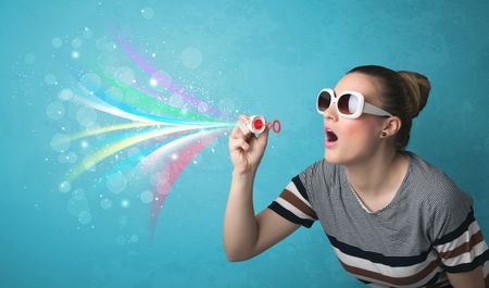 Beautiful girl blowing abstract colorful bubbles and lines on blue background