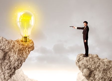 Businessman standing on the edge of mountain with an idea bulb on the other side
