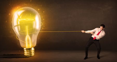 Business man pulling a big bright glowing light bulb concept on background